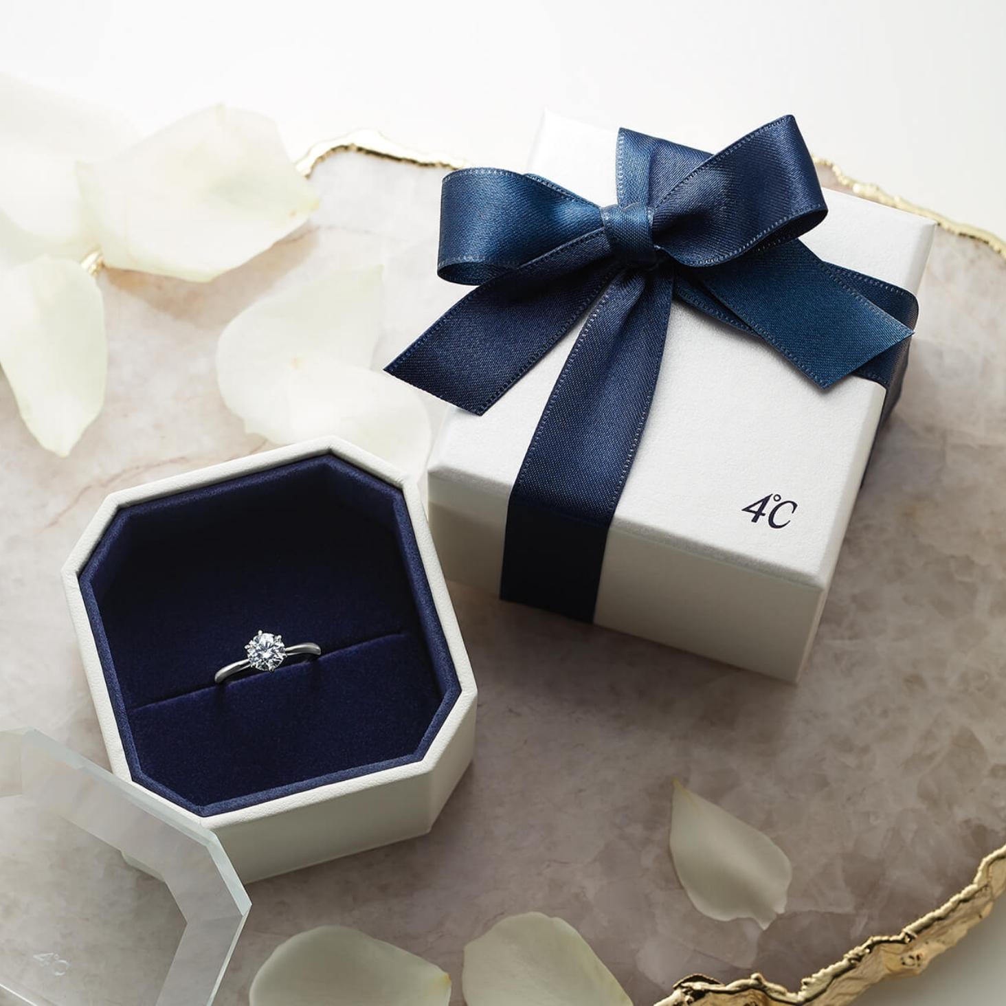4℃のリングケースに収められた婚約指輪と紺色のリボンのギフトボックス